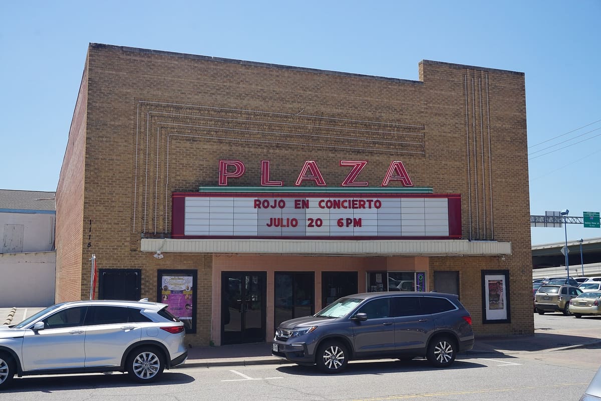 The Plaza Theater on the Carrollton square, a buff brick building with a red neon PLAZA sign and a white marquee above a recessed entrance