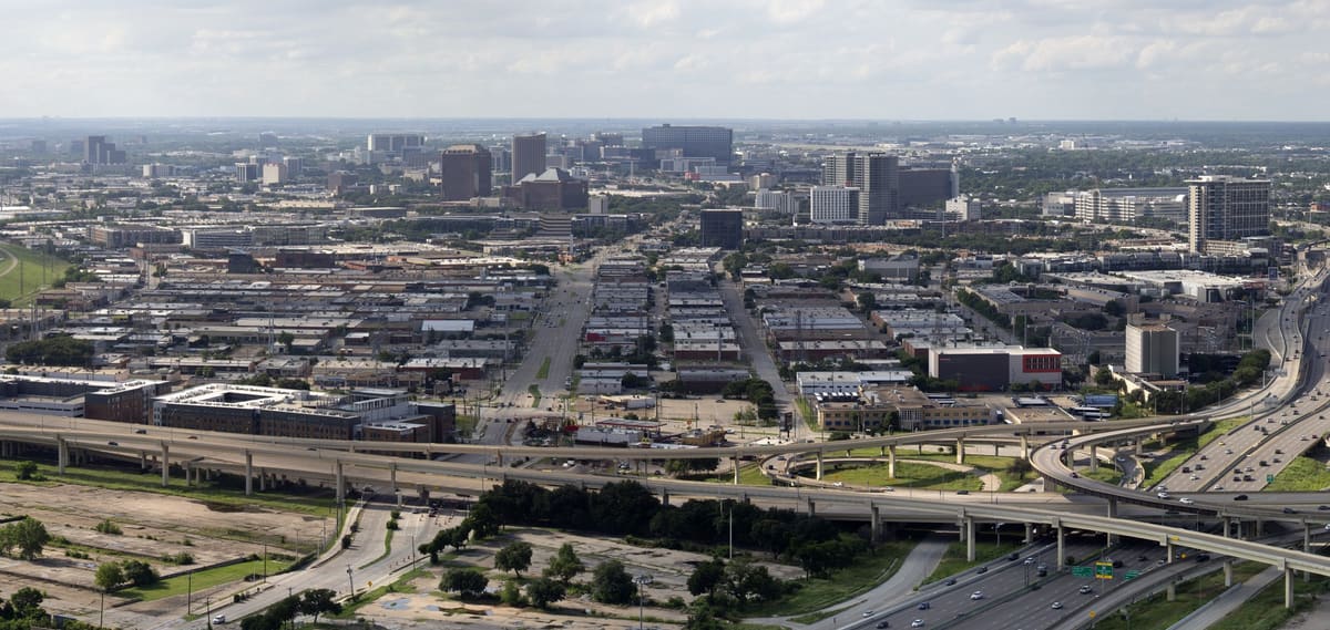 Rows of low warehouses and showrooms in the Dallas Design District seen from above, with freeways in the foreground