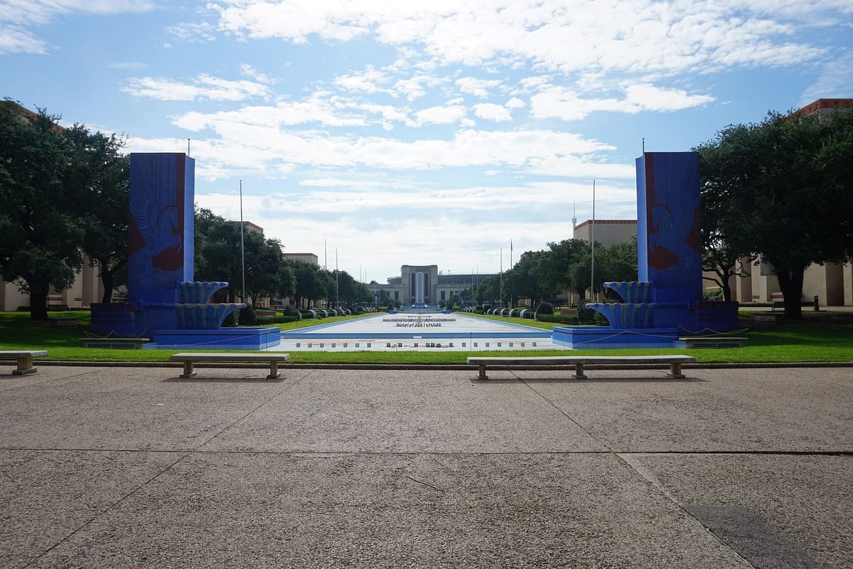 The Fair Park Esplanade reflecting pool flanked by blue Art Deco pylons, with the Hall of State at the far end