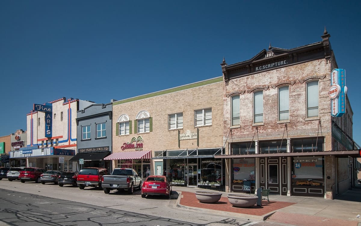 A row of historic storefronts on North Elm Street in Denton, including the 1882 R.C. Scripture building and the Fine Arts theater facade