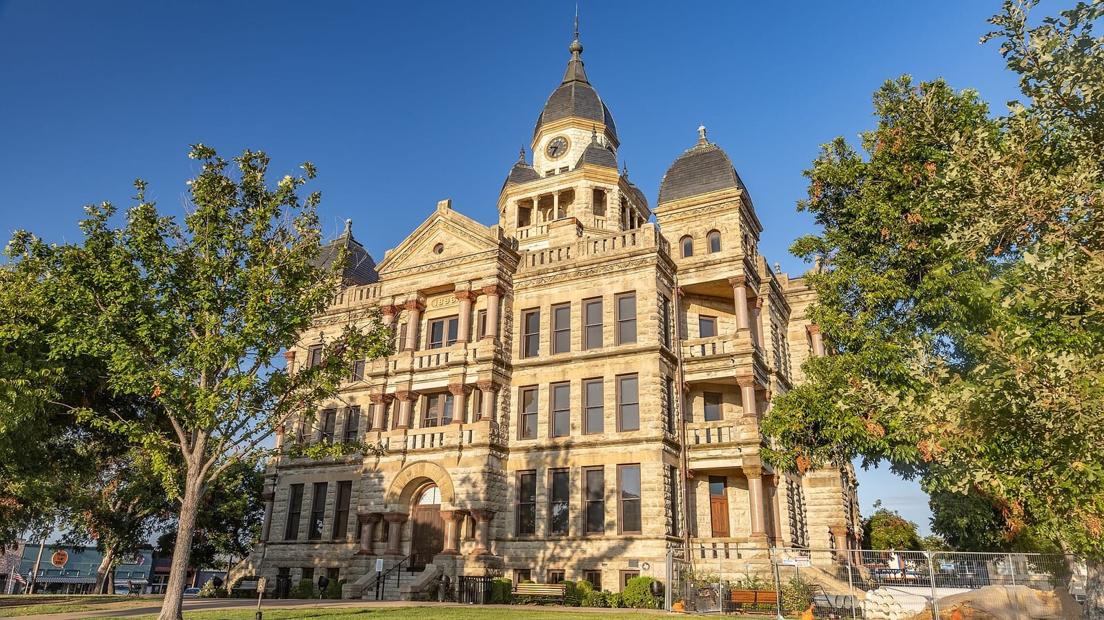 The 1896 Denton County Courthouse on the Denton square, a three-story Romanesque Revival building of cream limestone with red columns, corner turrets, and a clock tower
