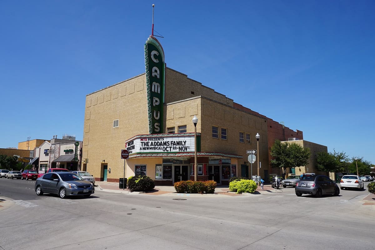 The Campus Theatre in Denton, a yellow brick Moderne building with a tall green and red CAMPUS blade sign over its marquee