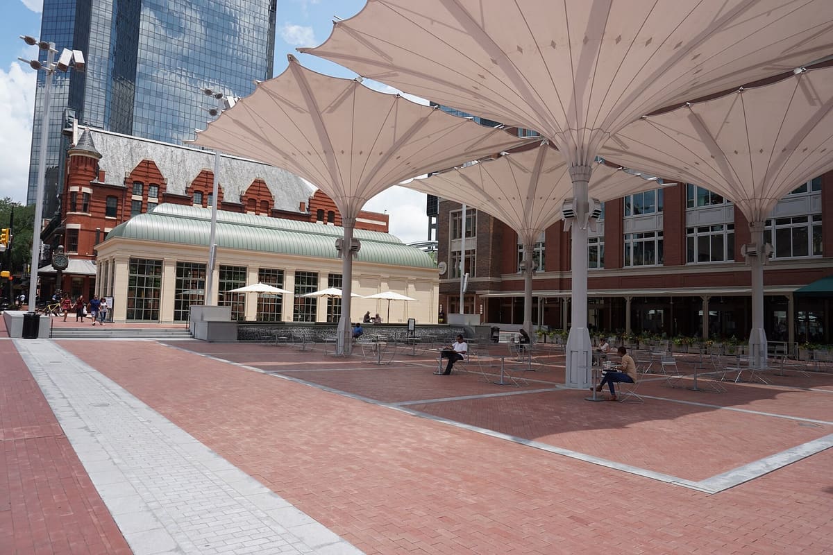 Sundance Square Plaza in downtown Fort Worth with large white canopy umbrellas over brick paving and historic red brick buildings behind