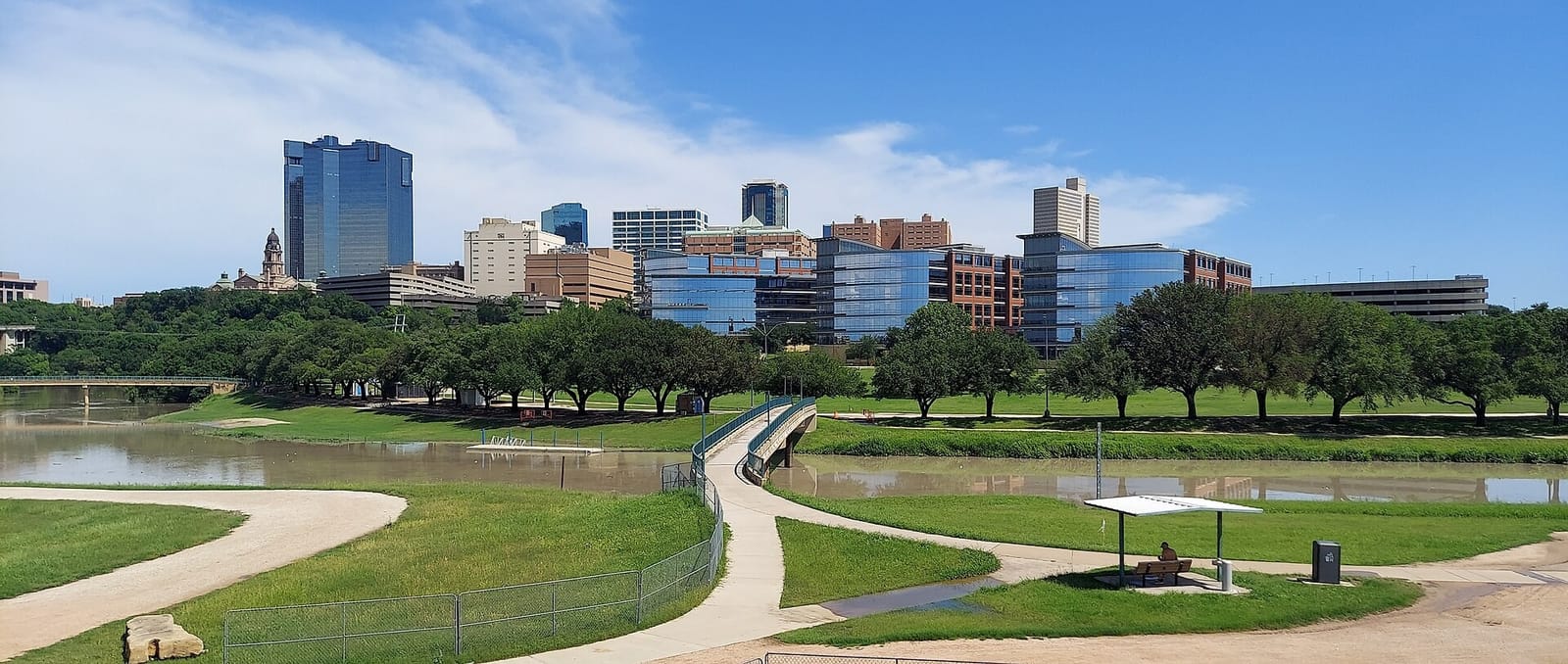Downtown Fort Worth skyline above the Trinity River and its trails, with the Tarrant County Courthouse clock tower on the bluff at left