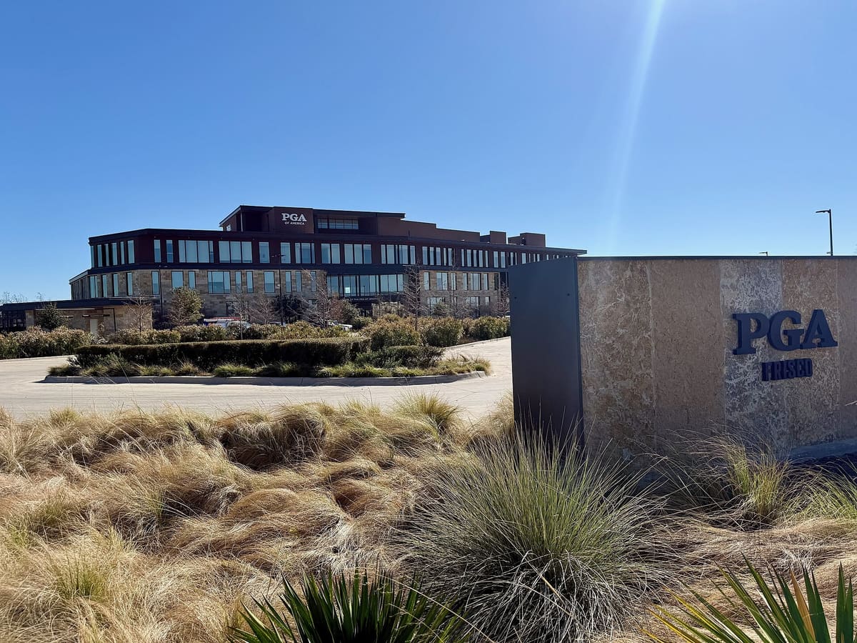 The PGA of America headquarters building behind a stone PGA Frisco monument sign and native grasses