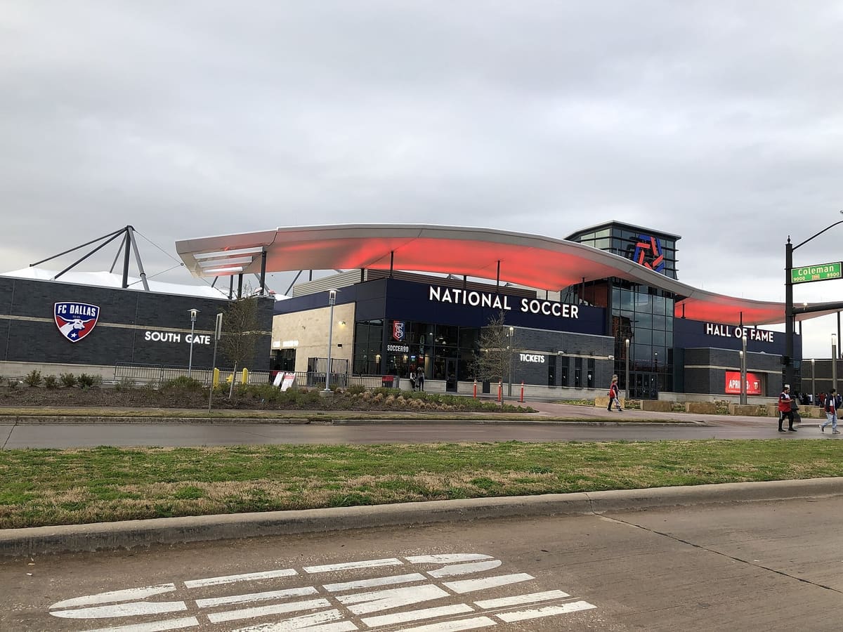 The National Soccer Hall of Fame entrance and South Gate at Toyota Stadium in Frisco under a red-lit canopy