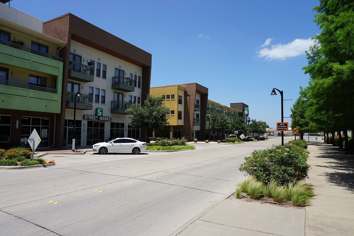 Fifth Street in downtown Garland, Texas, lined with four-story apartment buildings over ground-floor shops at 5th Street Crossing