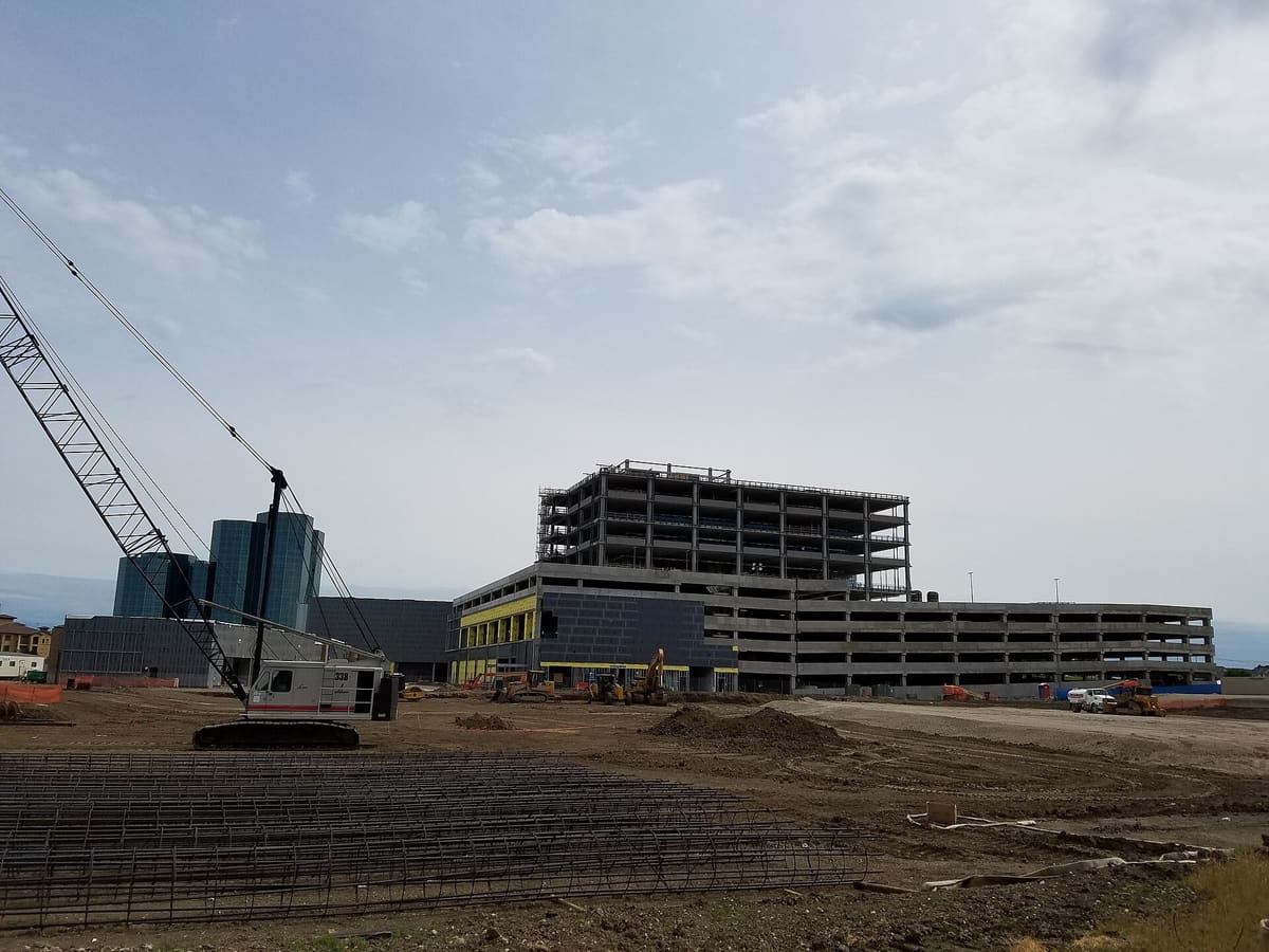 Toyota Music Factory under construction in May 2017, with a crawler crane, rebar cages on the ground, and a multi-level concrete structure rising
