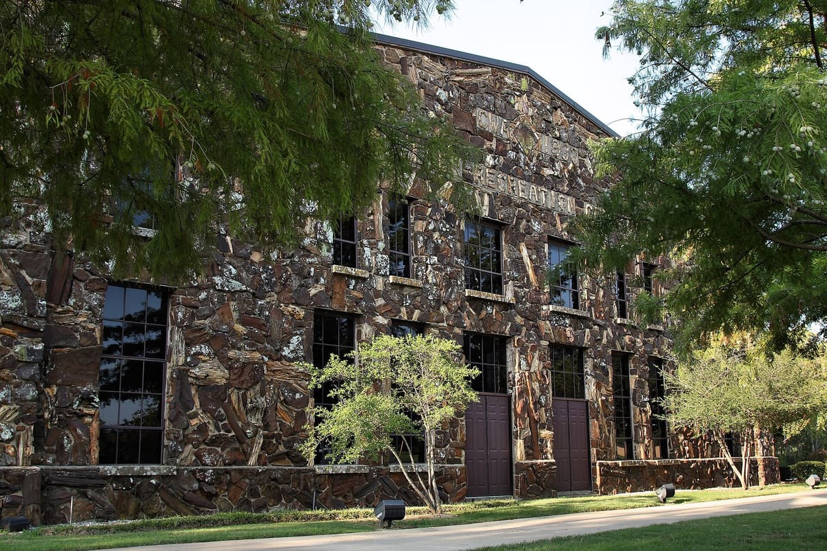The Keller Rock Gym, a two-story building of dark sandstone and petrified wood with tall multi-pane windows and CWA 1933 Recreation carved high on the facade