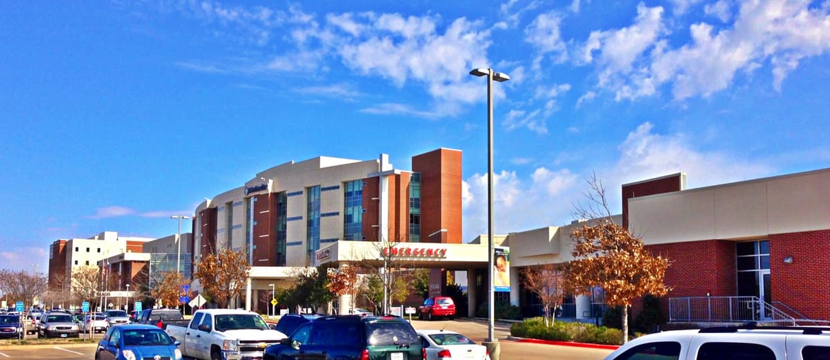 Methodist Mansfield Medical Center, a multistory brick and cream hospital building with an emergency entrance canopy, seen across a full parking lot