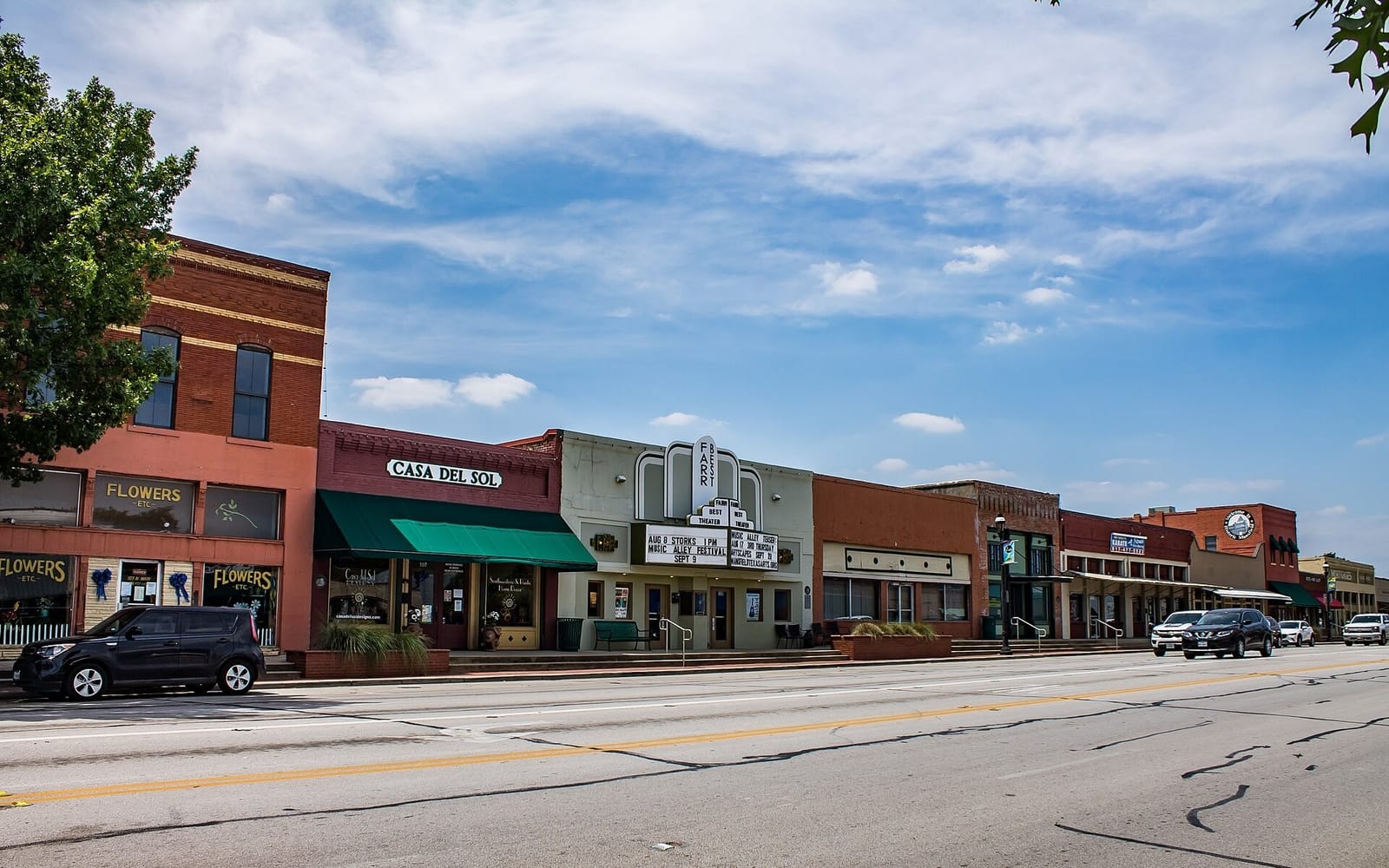 North Main Street in downtown Mansfield, Texas, with the Farr Best Theater marquee between one and two story red brick storefronts under a blue sky