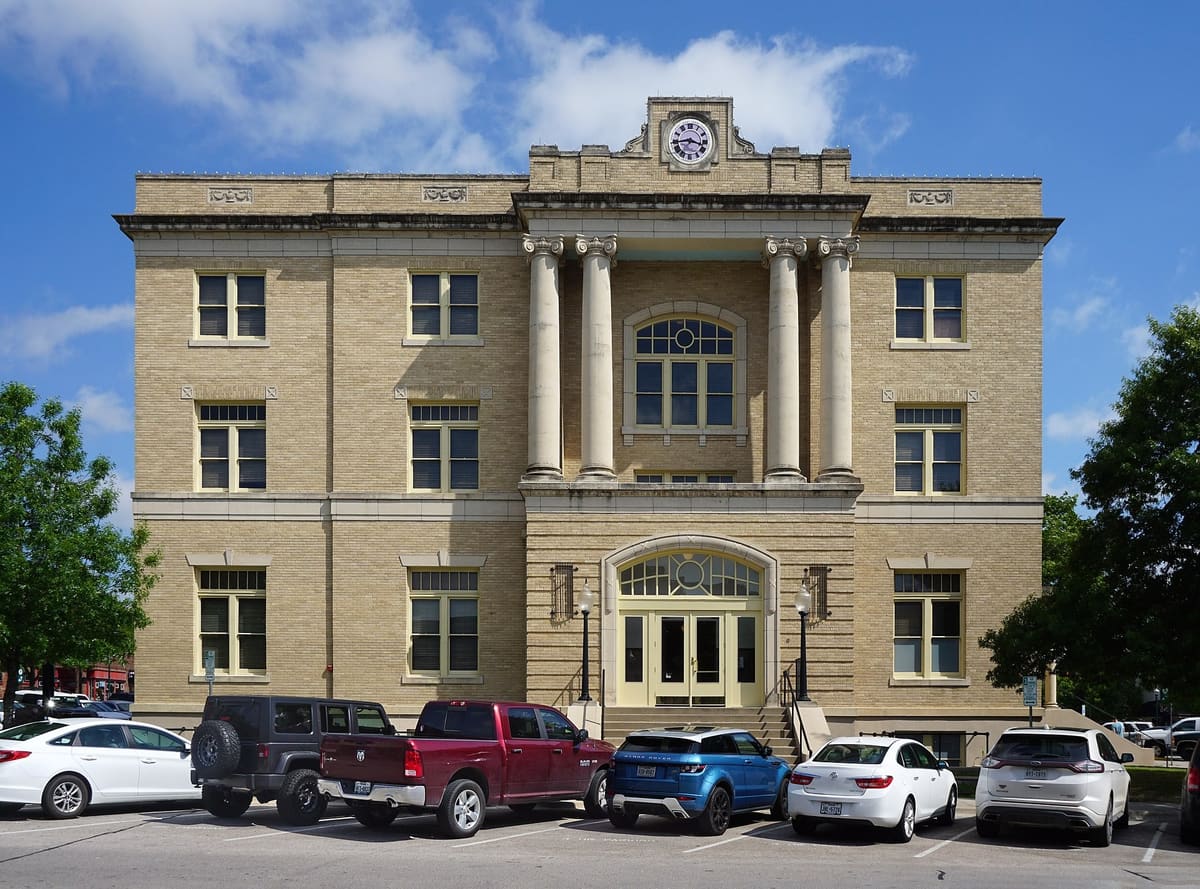 The Historic Collin County Courthouse on the McKinney square, a three-story buff brick building with Ionic columns and a clock, now the McKinney Performing Arts Center