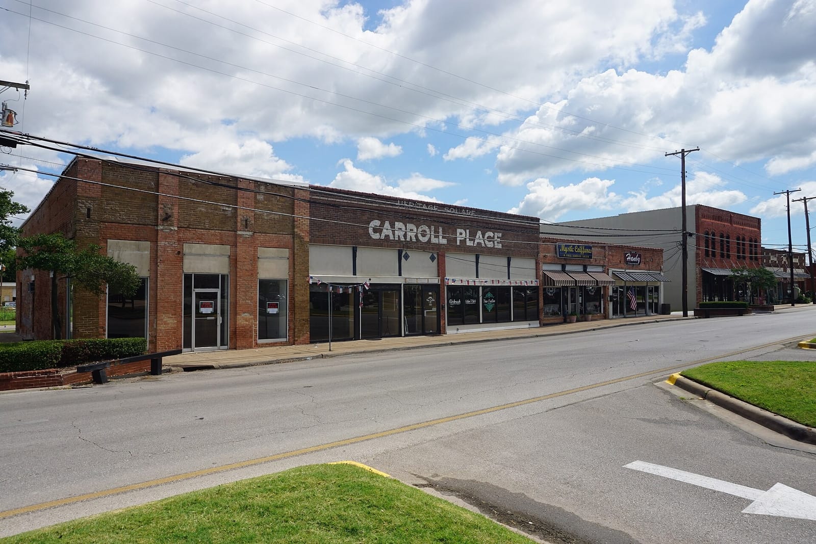 One-story brick storefronts on Main Street in downtown Mesquite, Texas, including the Carroll Place building with its painted sign