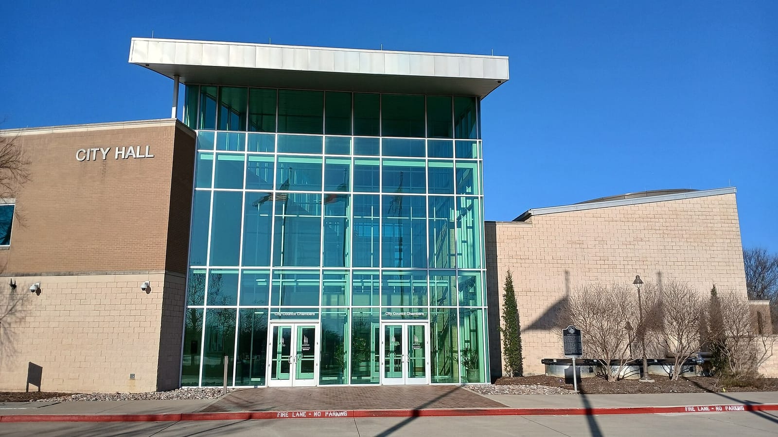 Murphy City Hall at 206 North Murphy Road, a tall glass atrium over the City Council Chambers doors between tan brick wings, with a Texas historical marker beside the entrance