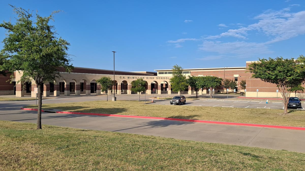 C.A. McMillen High School in Murphy, Texas, a long red brick and cast stone building with an arched entry arcade behind a wide lawn and young trees