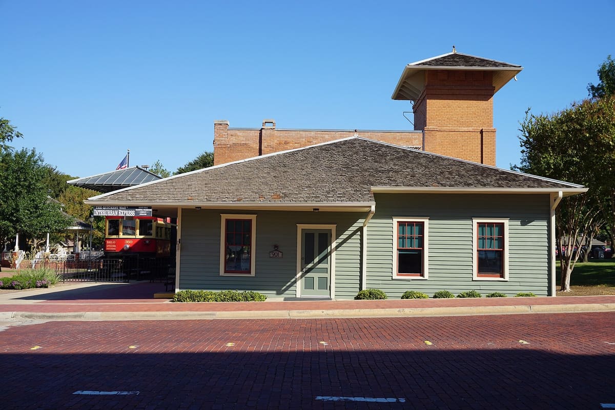 The Interurban Railway Museum, a green clapboard depot with a brick tower, beside a brick street in Plano
