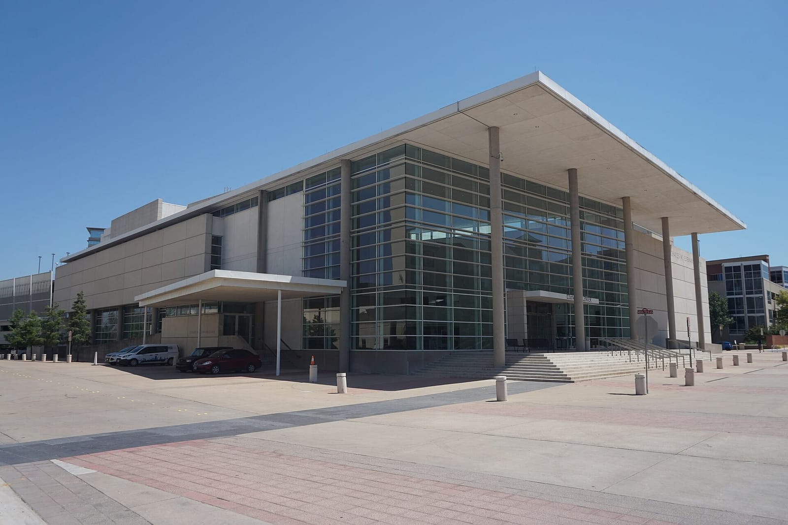 The Charles W. Eisemann Center for Performing Arts in Richardson, Texas, a pale stone and glass hall under a thin flat canopy roof held up by tall round columns
