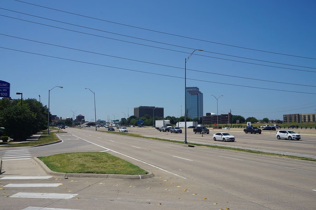 US 75, the North Central Expressway, in north Richardson with mid-rise and glass office towers of the Telecom Corridor beyond the frontage road