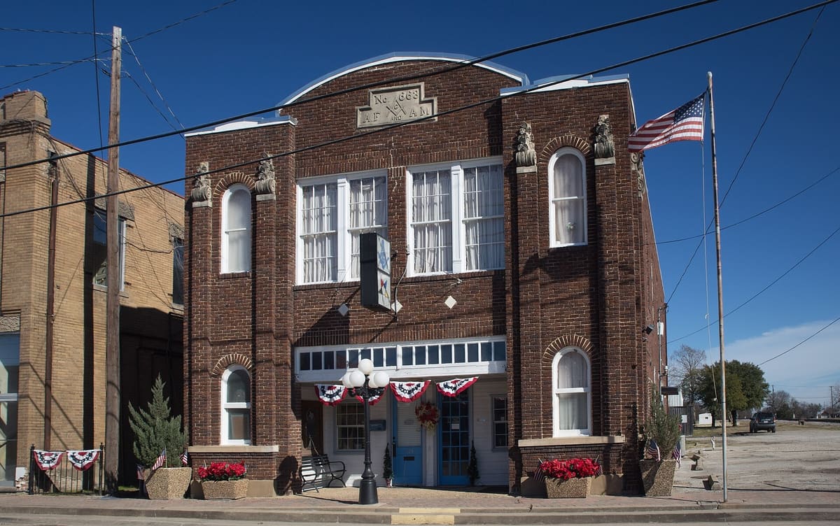 The 1925 Royse City Masonic Lodge No. 663, a two-story dark red brick building with arched windows, brick pilasters, and an A.F. and A.M. stone panel at the top