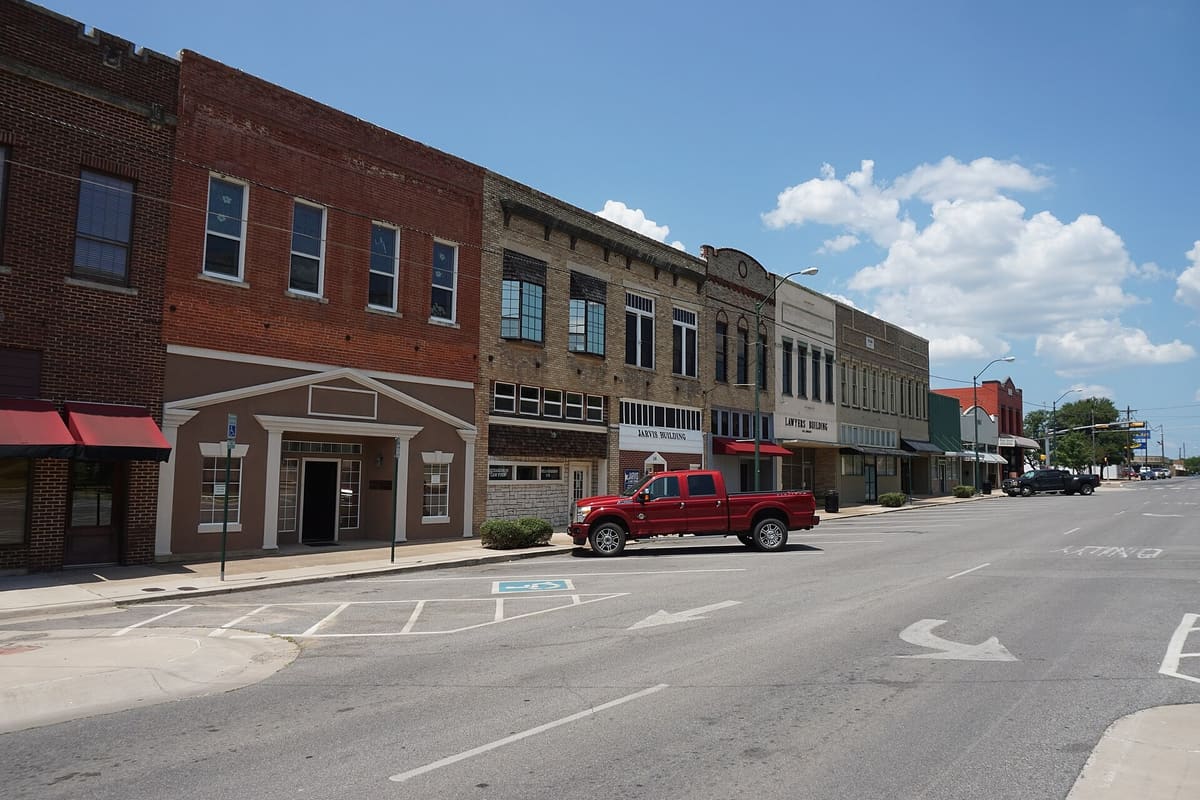 Two-story brick and tan brick storefronts on Crockett Street in downtown Sherman, including the Jarvis Building and the Lawyers Building, one refaced with stucco pilasters