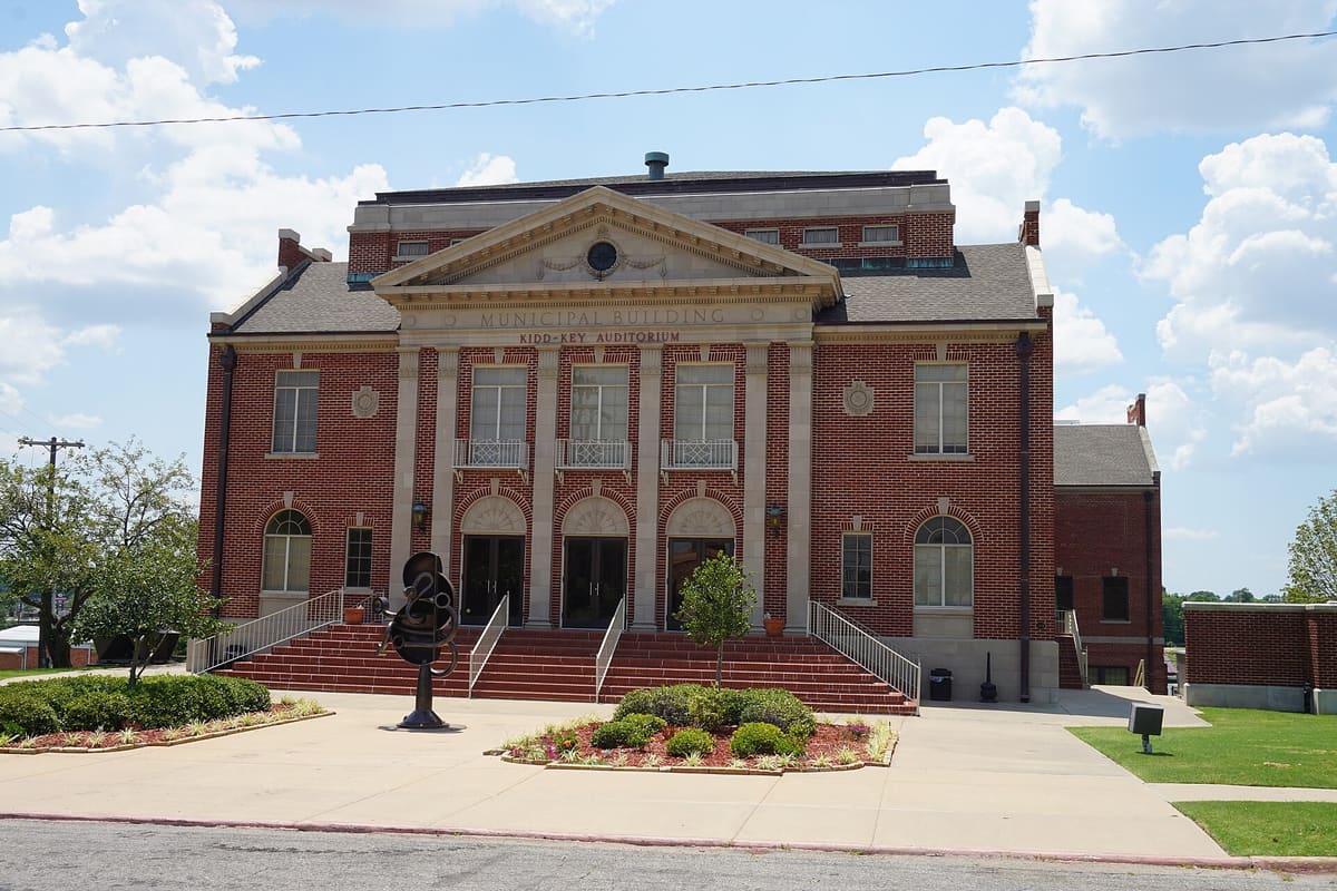 The red brick Municipal Building in Sherman with a limestone pediment, Kidd-Key Auditorium lettering, three arched entrances, and wide front steps