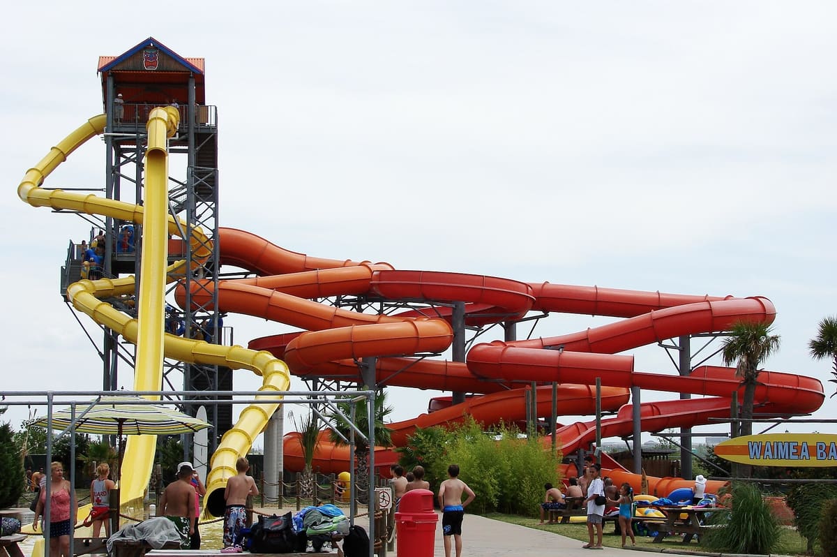 Yellow and orange tube slides wrapping around a tall steel slide tower at the Paige Road waterpark