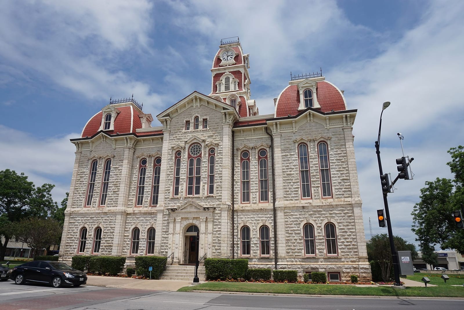 The 1886 Parker County Courthouse in Weatherford, Texas, a three-story limestone building with red mansard roofs and a central clock tower under a blue sky