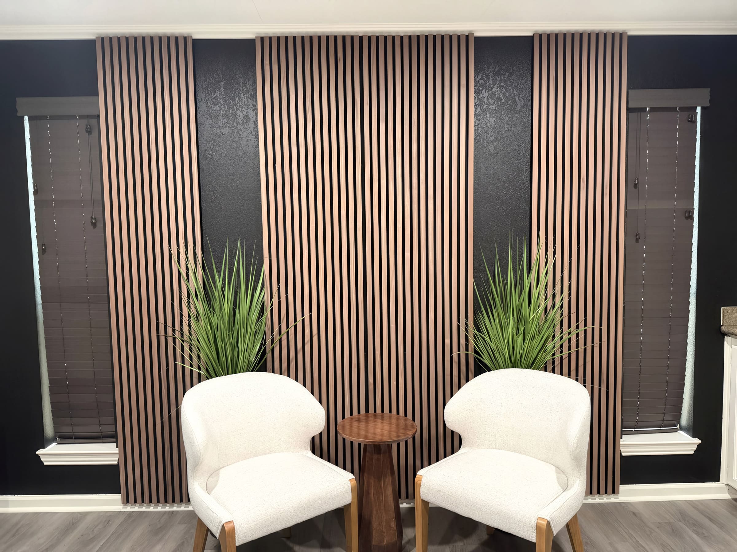 A finished seating nook with slatted wood wall panels, two upholstered chairs, and a small side table