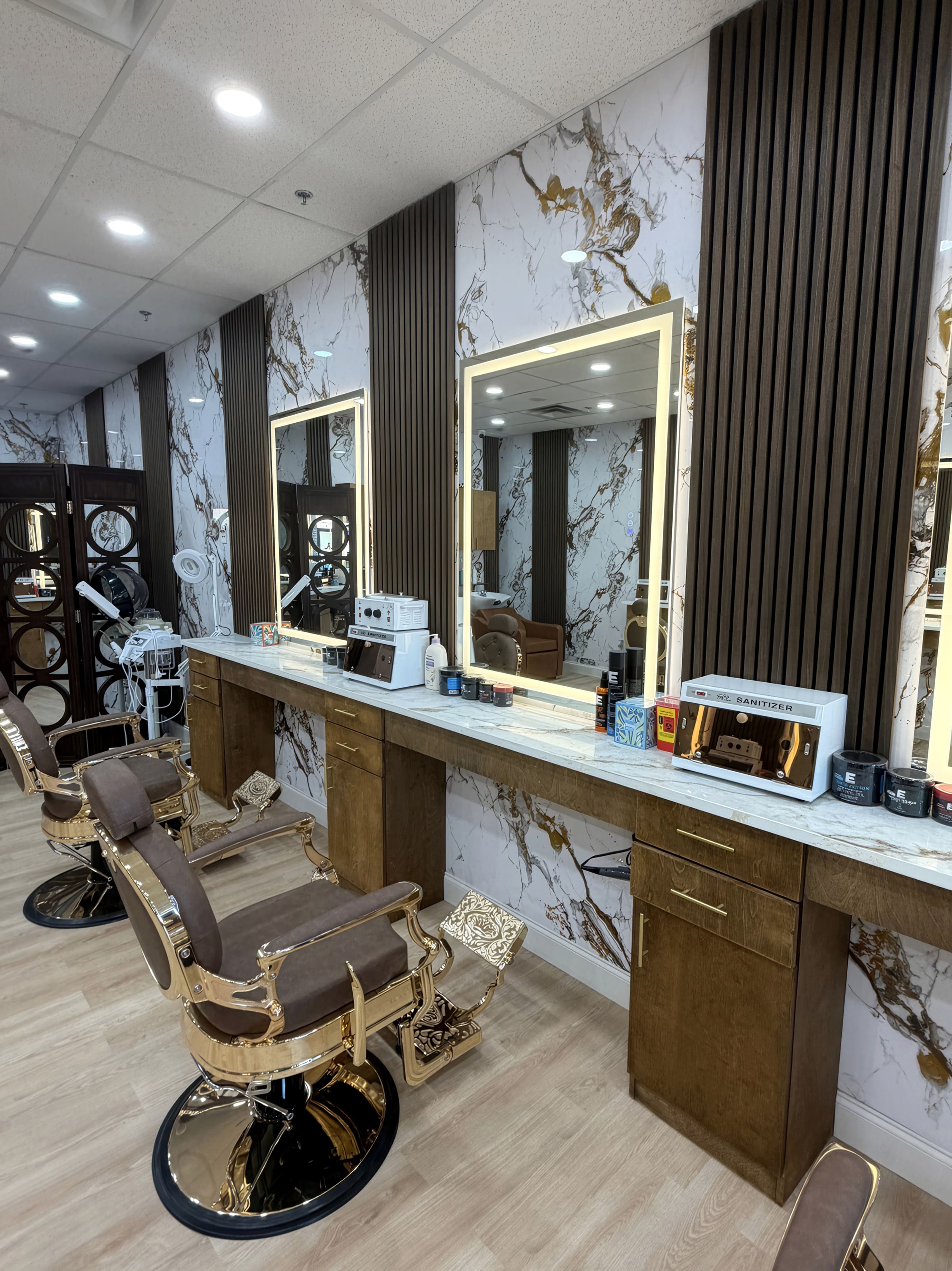 Barber stations at the Fade & Style build-out in Allen, Texas, with marble-look station walls, gold framed mirrors, and leather chairs